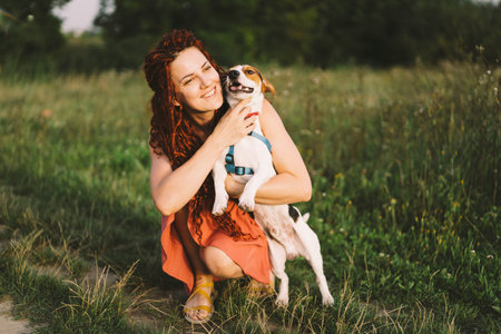 Beautiful woman plays with her Jack Russell dog in the park.の写真素材