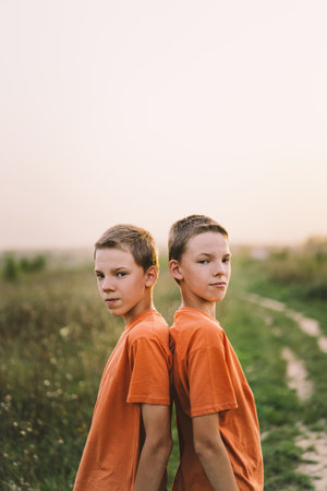 Funny twin brother boys playing outdoors on field at sunset.の写真素材