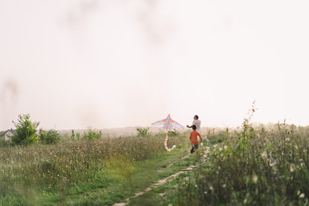 Happy family and children run on meadow with a kite in the summer on the nature.の写真素材