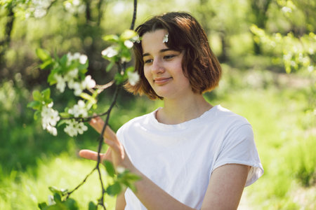Beautiful teenage girl with spring flowers enjoying nature and laughing on spring garden