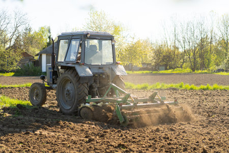 The tractor drives across the field and cultivates the land.の写真素材