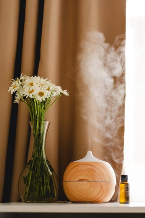 Aromatherapy concept. Aroma oil diffuser on the table against the window.の写真素材