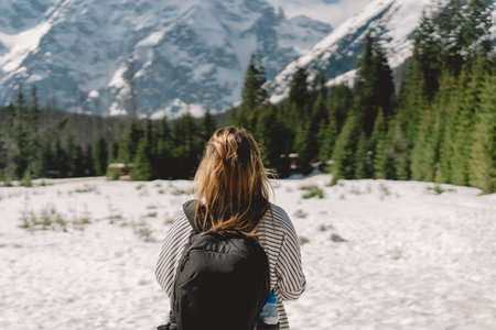 Back view of a girl traveler wearing a backpack traveling aloneの写真素材