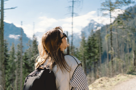 Back view of a girl traveler wearing a backpack traveling aloneの写真素材