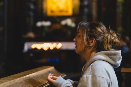 Woman praying on her knees in an ancient Catholic temple to God.の素材 [FY310204938429]