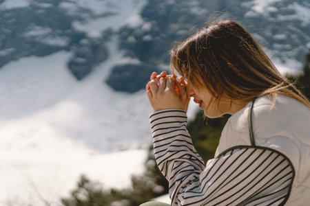 Woman closed her eyes, praying near the mountain.の写真素材