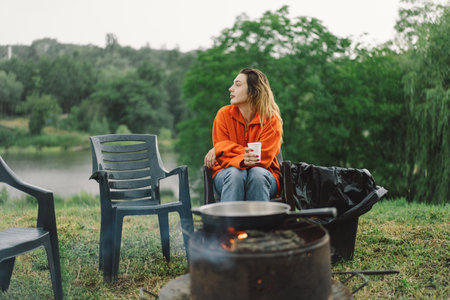 A woman enjoy the tea by the fire in rainy weather.