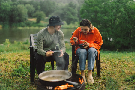 A man and a woman enjoy the food by the fire.の写真素材