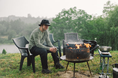 A man enjoy the tea by the fire in rainy weather.の写真素材