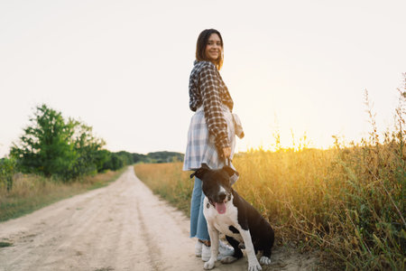 Human and a dog. Teengirl and her friend staffer dog on the field backgroundの写真素材
