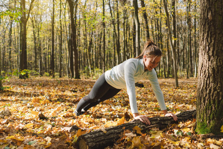 Girl doing fitness in nature on a sunny autumn forestの写真素材