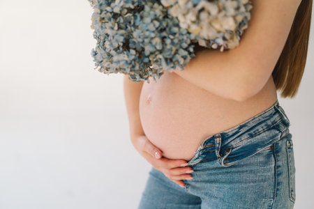 Pregnant girl with flowers in the cleavage area. Pregnant womanの写真素材