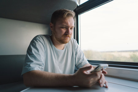 A man using a smartphone while traveling by Railway train