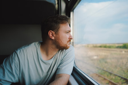 A man in a blue t-shirt while traveling by Railway trainの写真素材