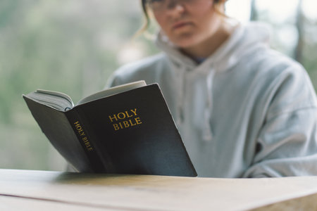 A girl reads the Bible against the background of a beautiful forest panorama.の写真素材