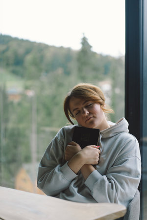 A girl reads the Bible against the background of a beautiful forest panorama.の写真素材