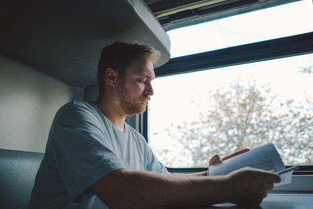 A man is reading a book while traveling by Railway trainの写真素材