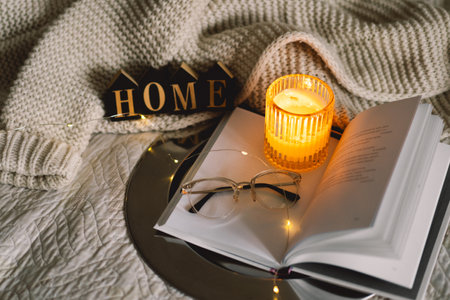 Sweet home. Scented candle with book with folded sheets in heart shape in bedの写真素材