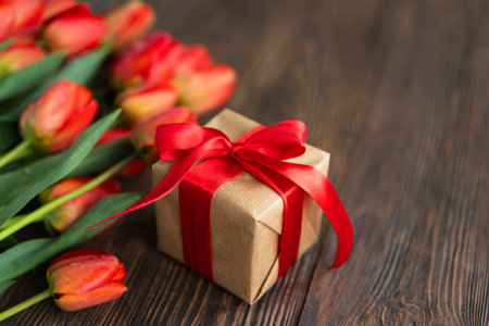 Bouquet of tulips with gift boxe and red hearts on wood background.の写真素材