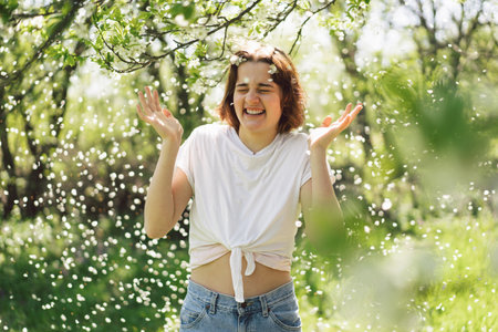 Beautiful teenage girl with spring flowers enjoying nature and laughing on spring gardenの写真素材