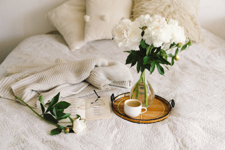 Open book with glasses, cup coffee and bouquet white pink peonies flowersの写真素材