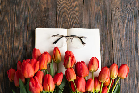 Fresh orange tulips with open book or diary on wooden backgroundの写真素材