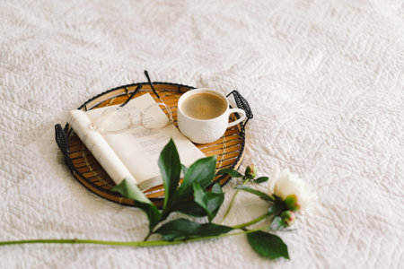 Open book with glasses, cup coffee and bouquet white pink peonies flowersの写真素材
