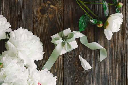 Bouquet of beautiful white peonies with gift boxes on wood backgroundの写真素材