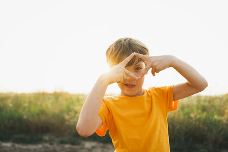 Portrait of a smiling little boy in an orange T-shirt playing outdoors