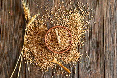 Ears of wheat and bowl of wheat grains on wooden backgroundの写真素材
