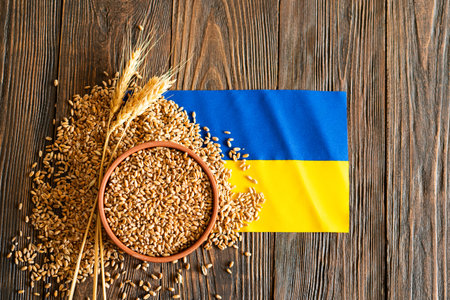 Wheat grains with yellow and blue Ukrainian flag on wooden backgroundの写真素材
