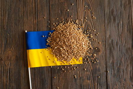 Wheat grains with yellow and blue Ukrainian flag on wooden backgroundの写真素材