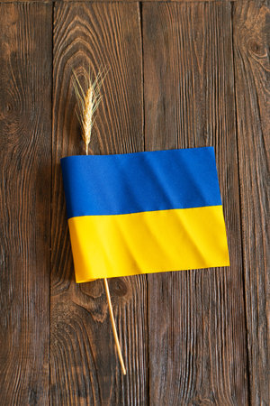 Wheat grains with yellow and blue Ukrainian flag on wooden backgroundの写真素材