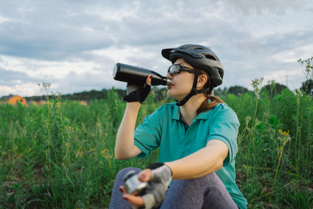 Woman in Helmet Takes a Drink During a Bike Rideの写真素材