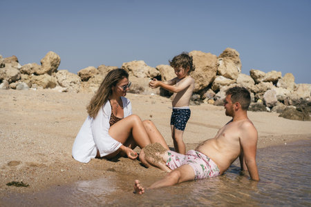 Family Playing on a Sandy Beach in the Sunの写真素材