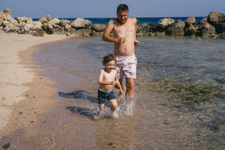 Father is playing with Son on a Sunny Beachの写真素材