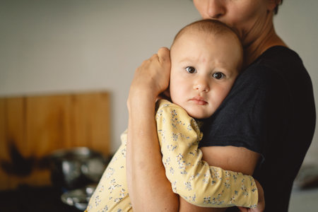 Mother Holding a Toddler In a Modern Kitchenの写真素材