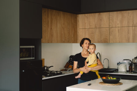 Mother Holding a Toddler In a Modern Kitchenの写真素材