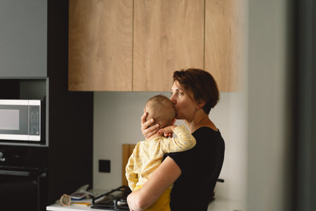 Mother Holding a Toddler In a Modern Kitchen