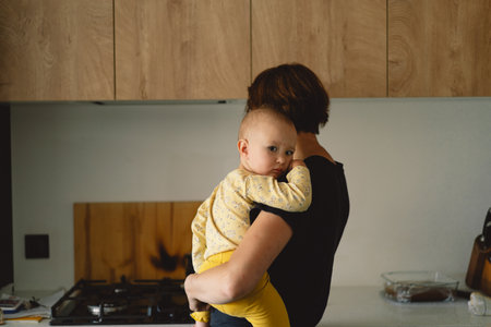 Mother Holding a Toddler In a Modern Kitchenの写真素材