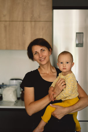 Mother Holding a Toddler In a Modern Kitchenの写真素材