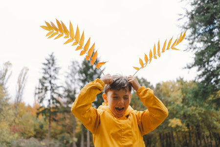 A cheerful child in a yellow raincoat walks through the forestの写真素材