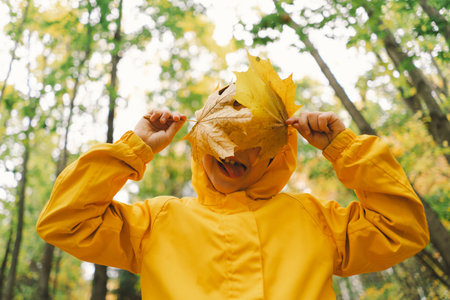 A cheerful child in a yellow raincoat walks through the forest