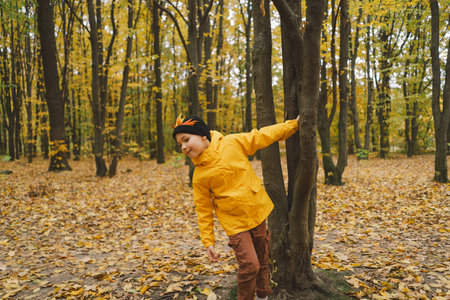 A cheerful child in a yellow raincoat walks through the forestの写真素材