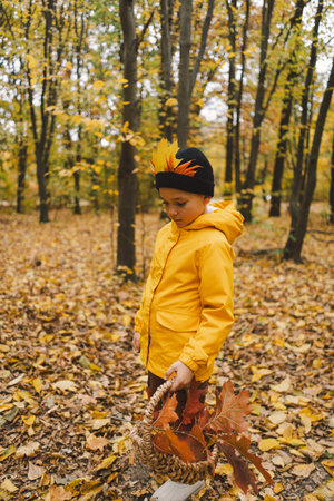 A cheerful child in a yellow raincoat walks through the forestの写真素材