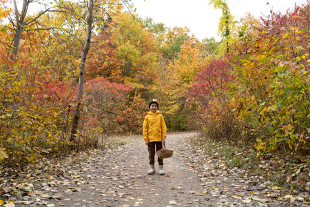 A cheerful child in a yellow raincoat walks through the forestの写真素材