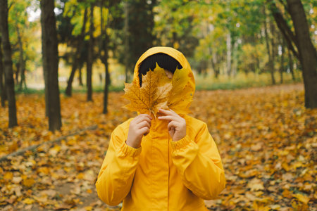 A cheerful child in a yellow raincoat walks through the forestの写真素材