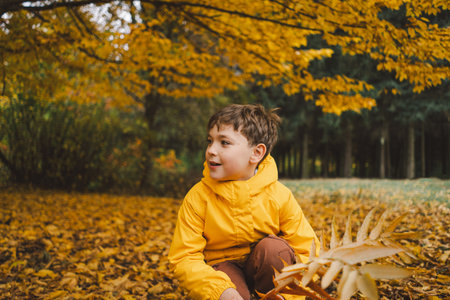 A cheerful child in a yellow raincoat walks through the forestの写真素材