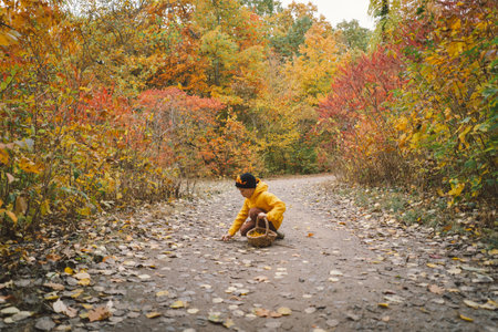 A cheerful child in a yellow raincoat walks through the forestの写真素材