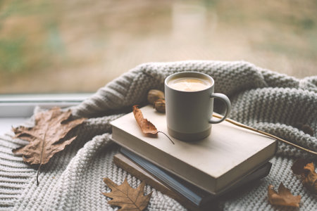 A cozy moment with a warm cup of coffee on a stack of booksの写真素材